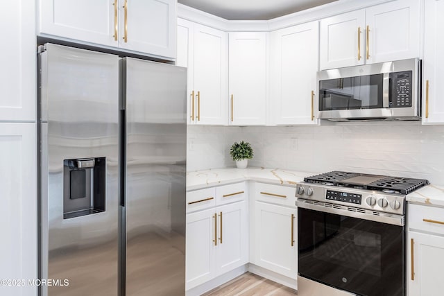 kitchen featuring white cabinetry, appliances with stainless steel finishes, light stone counters, and tasteful backsplash