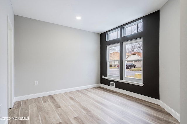 empty room with baseboards, visible vents, and light wood-style flooring