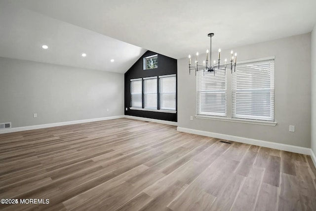 unfurnished dining area with an inviting chandelier, baseboards, wood finished floors, and visible vents