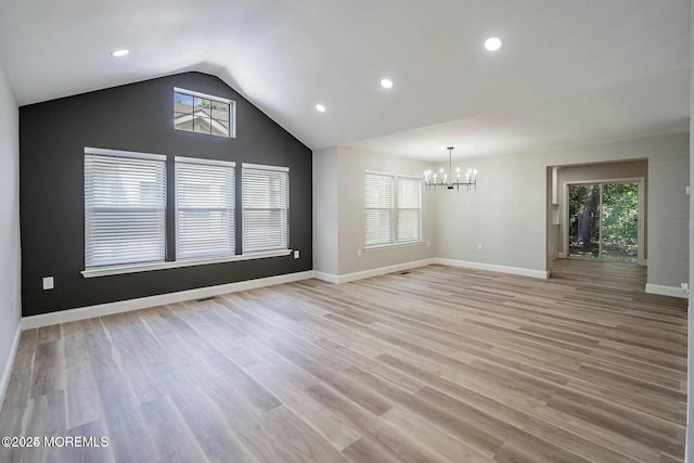 unfurnished living room featuring a chandelier, plenty of natural light, light wood finished floors, and lofted ceiling