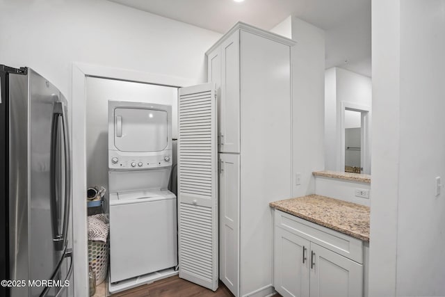 laundry area with laundry area, dark wood finished floors, and stacked washer and clothes dryer