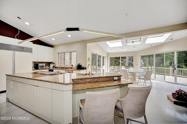 44 Nikki Ct, Morganville, NJ 07751 - kitchen with white cabinetry, a sink, a spacious island, light stone countertops, and lofted ceiling with skylight