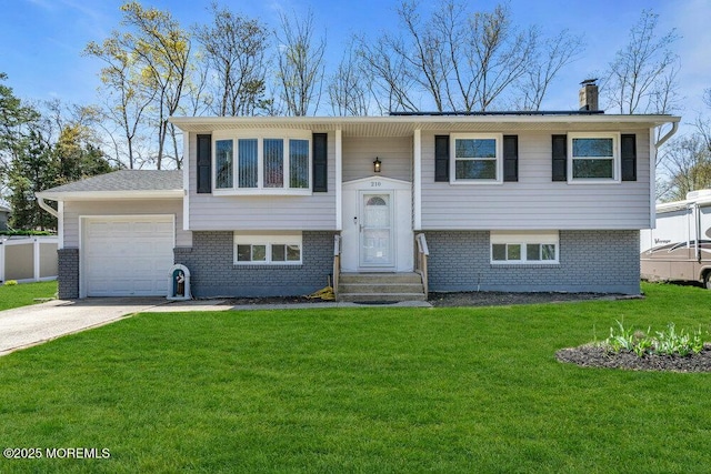 raised ranch with a front yard, a chimney, an attached garage, and brick siding