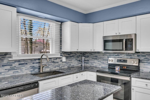 kitchen with appliances with stainless steel finishes, white cabinets, backsplash, a sink, and crown molding