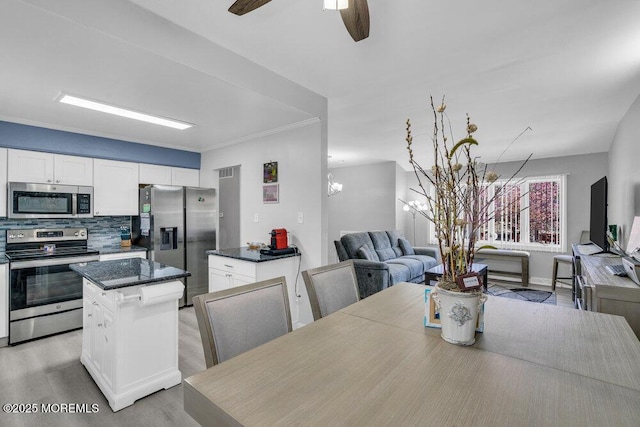 dining area featuring light wood-type flooring, ornamental molding, and ceiling fan with notable chandelier