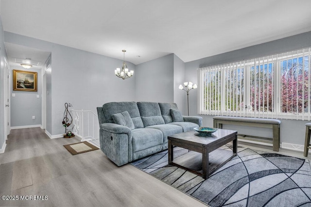 living room with baseboards, wood finished floors, and an inviting chandelier