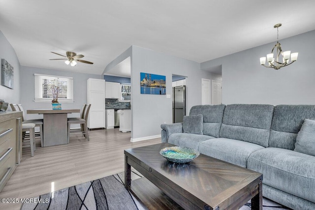 living room featuring baseboards, light wood-style flooring, and ceiling fan with notable chandelier