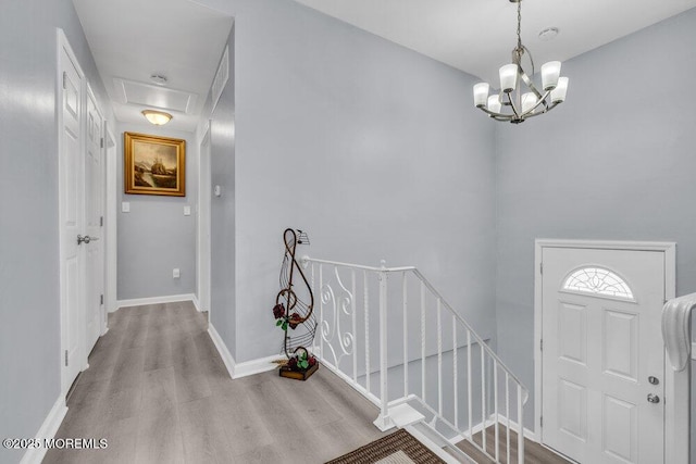 entrance foyer with baseboards, wood finished floors, and a notable chandelier