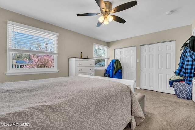 bedroom with ceiling fan, carpet floors, and multiple closets