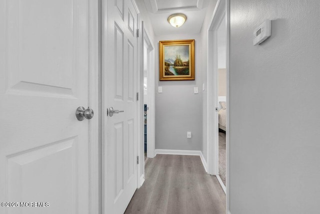 corridor featuring wood finished floors and baseboards