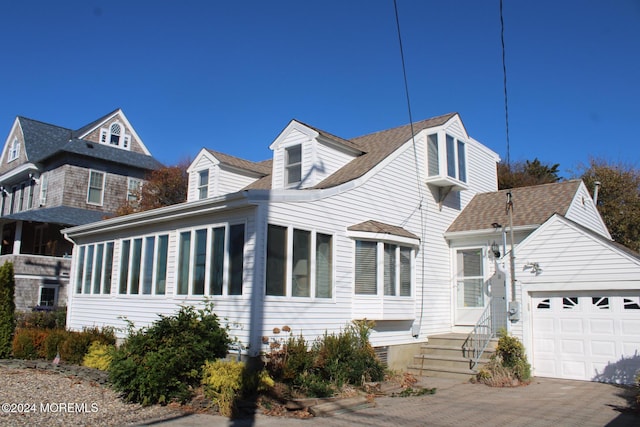 view of front facade with an attached garage, a shingled roof, and driveway