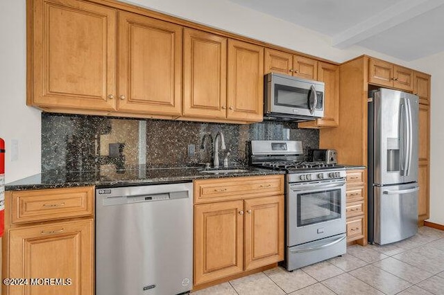 kitchen featuring a sink, appliances with stainless steel finishes, tasteful backsplash, and dark stone countertops