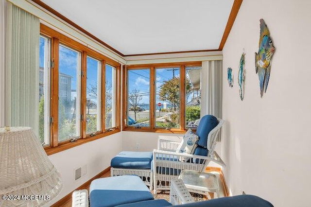 sunroom with baseboards, visible vents, and ornamental molding
