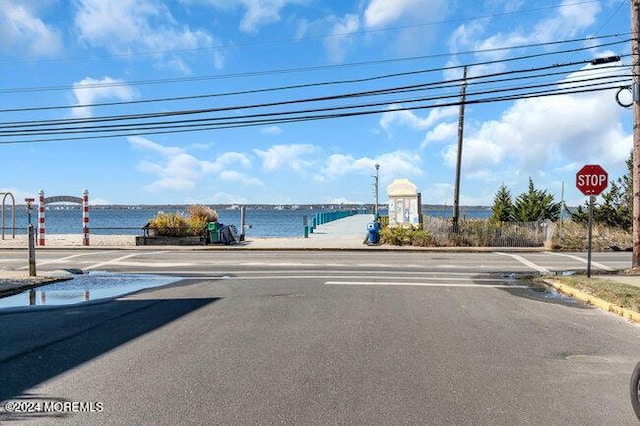 view of street featuring a water view, sidewalks, traffic signs, and curbs