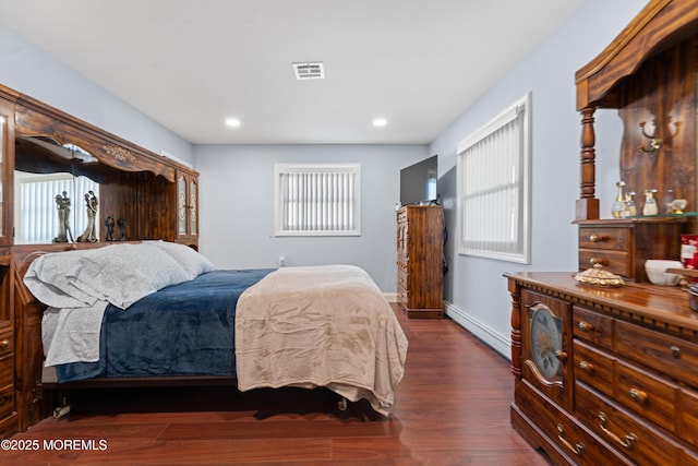 bedroom featuring a baseboard heating unit, dark wood-style flooring, baseboards, visible vents, and recessed lighting