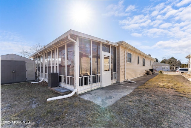view of property exterior with an outdoor structure, a sunroom, and a shed