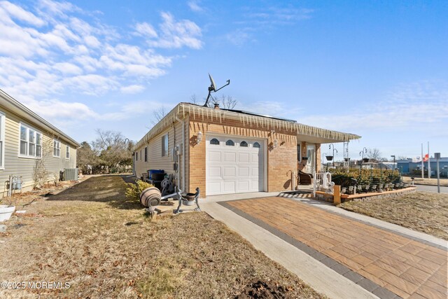 view of property exterior with brick siding, an attached garage, and aphalt driveway