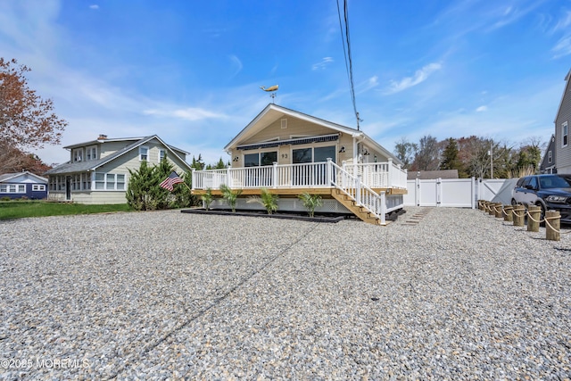 back of house with a deck, fence, and a gate