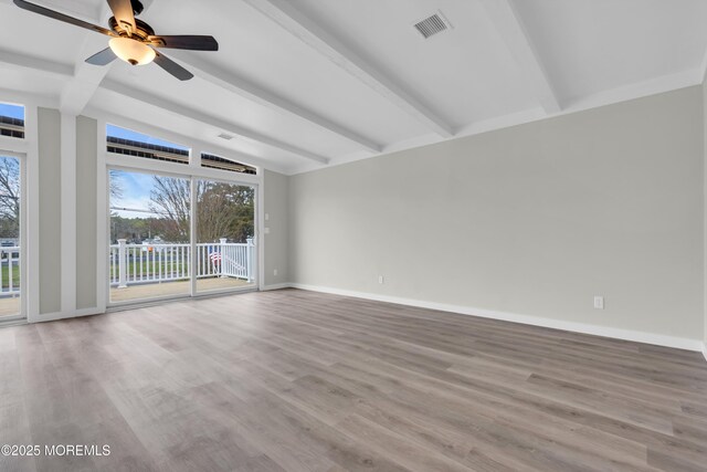 spare room featuring wood finished floors, visible vents, ceiling fan, and vaulted ceiling with beams