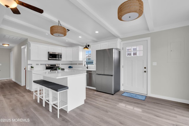 kitchen with white cabinets, visible vents, stainless steel appliances, light countertops, and a center island