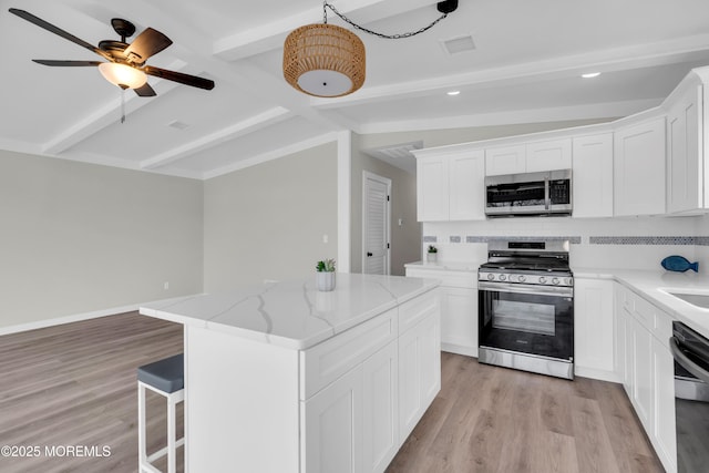 kitchen featuring appliances with stainless steel finishes, visible vents, vaulted ceiling with beams, and light wood-style floors