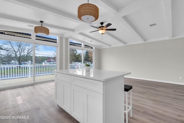 kitchen featuring a center island, light wood finished floors, visible vents, and white cabinetry