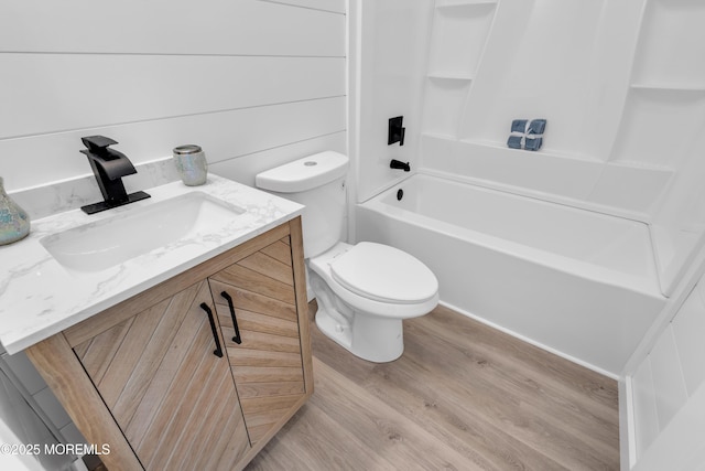 bathroom featuring wood finished floors, toilet, shower / tub combination, and vanity