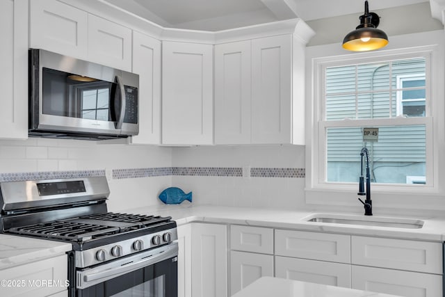 kitchen with stainless steel appliances, decorative backsplash, white cabinets, and a sink