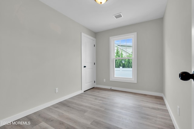unfurnished room featuring wood finished floors, visible vents, and baseboards