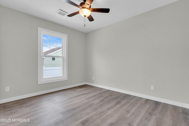 unfurnished room featuring baseboards, visible vents, wood finished floors, and ceiling fan
