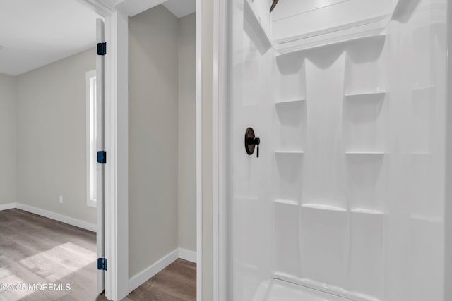 bathroom with walk in shower, wood finished floors, and baseboards