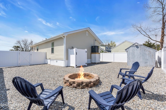 exterior space featuring a fenced backyard, a gate, a fire pit, a storage unit, and crawl space