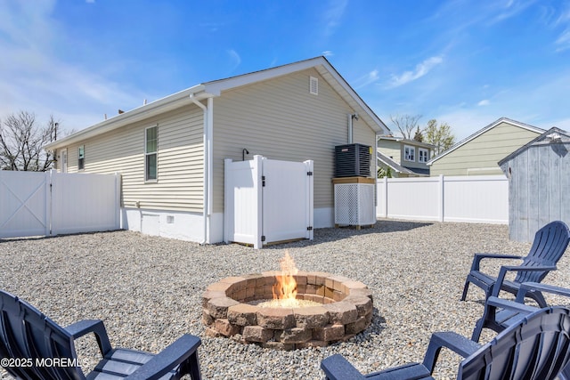 view of home's exterior with a fire pit, a storage unit, a gate, an outbuilding, and a fenced backyard