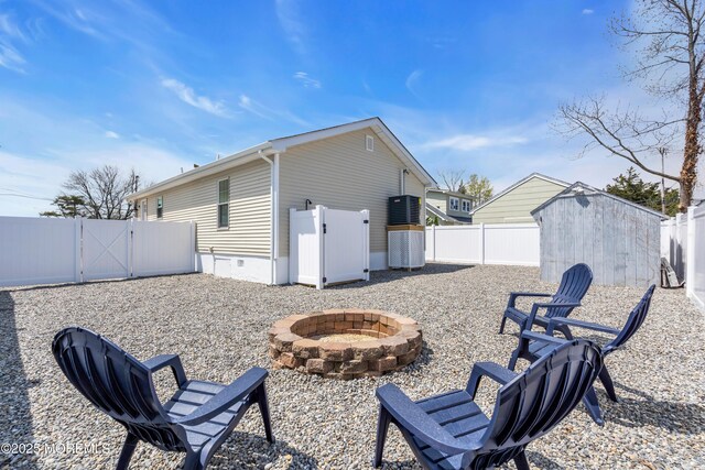 exterior space with a gate, an outbuilding, a storage shed, an outdoor fire pit, and a fenced backyard