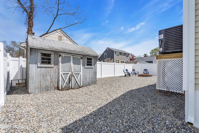 view of yard with a fire pit, an outbuilding, a storage shed, central AC unit, and a fenced backyard