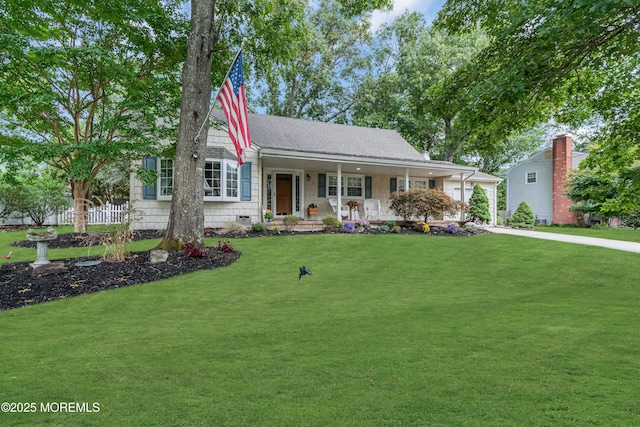 view of front of property featuring roof with shingles, covered porch, and a front yard