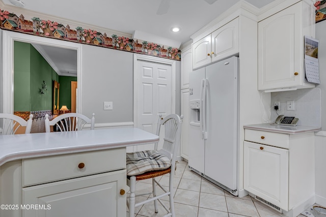 kitchen featuring ornamental molding, white refrigerator with ice dispenser, light countertops, white cabinetry, and light tile patterned floors