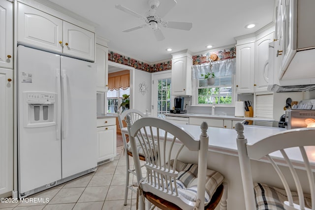 kitchen with light tile patterned floors, light countertops, white fridge with ice dispenser, and white cabinetry