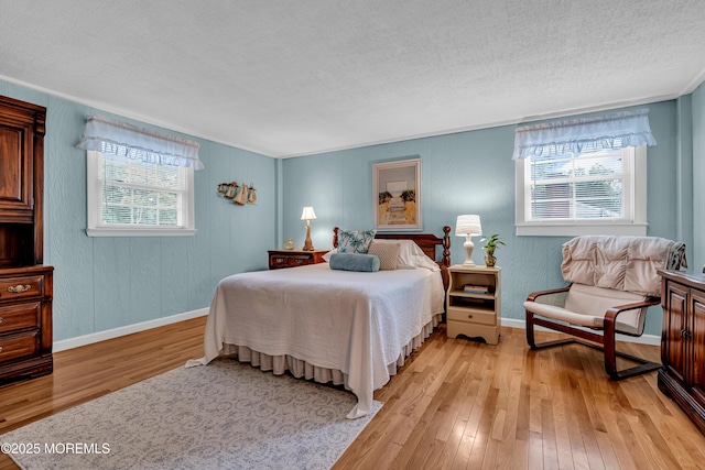 bedroom featuring light wood-style floors, baseboards, and a textured ceiling