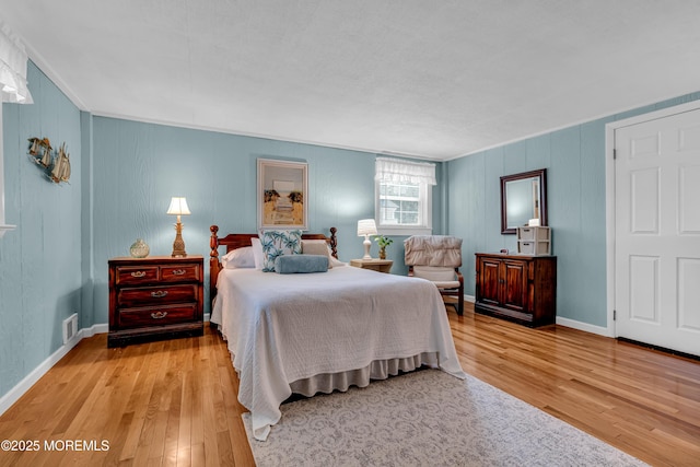 bedroom featuring visible vents, baseboards, and wood finished floors