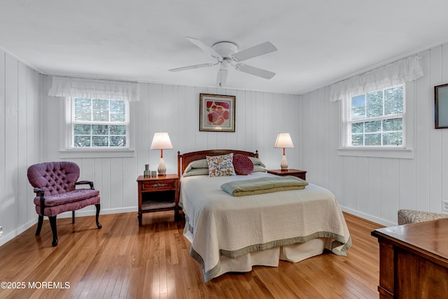 bedroom with baseboards, multiple windows, wood-type flooring, and a ceiling fan