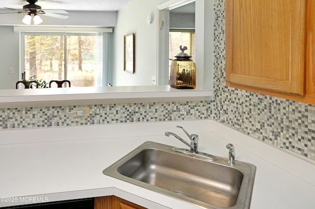 kitchen with ceiling fan, tasteful backsplash, light countertops, and a sink