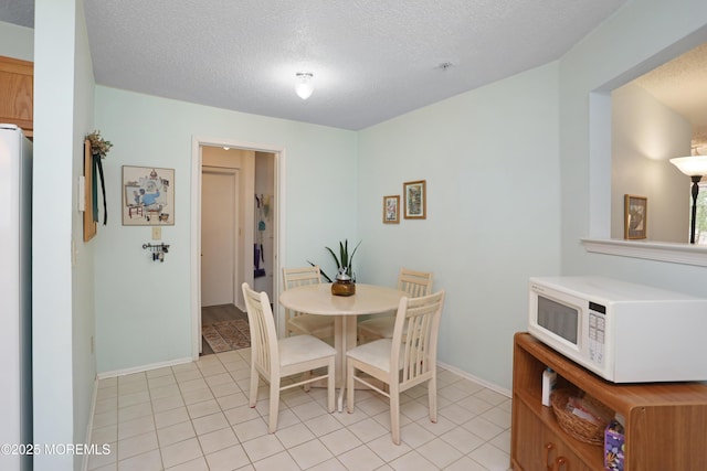 dining room featuring light tile patterned floors, a textured ceiling, and baseboards
