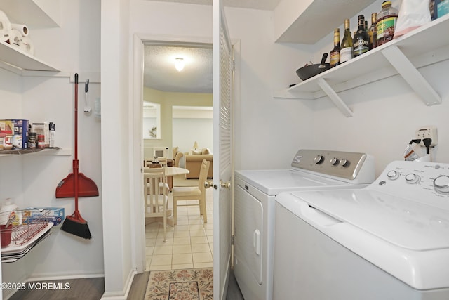 laundry area featuring light tile patterned flooring, washer and dryer, laundry area, and baseboards
