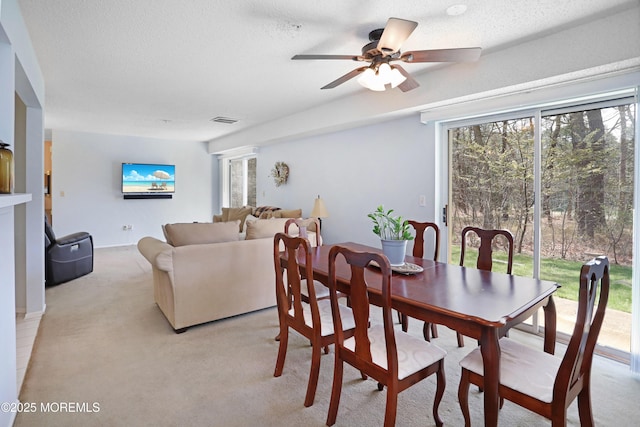 dining space with visible vents, a ceiling fan, light carpet, and a textured ceiling