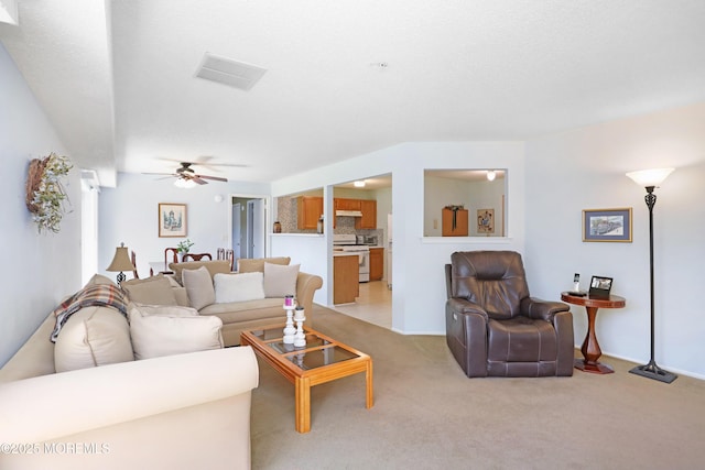 living room featuring visible vents, ceiling fan, and light colored carpet