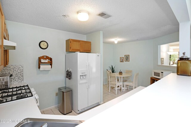 kitchen with white appliances, visible vents, baseboards, light countertops, and a textured ceiling