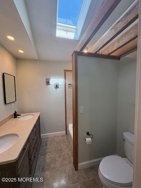 full bathroom with a skylight, toilet, baseboards, and a sink
