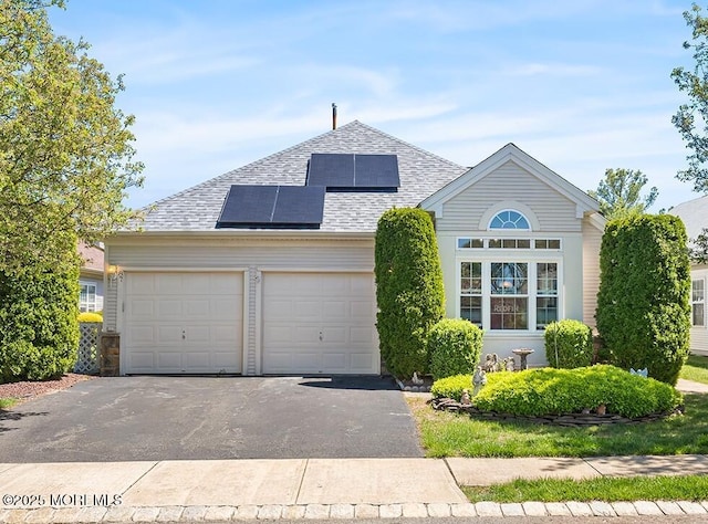 87 Halsted Dr, Manchester, NJ 08759 - view of front of home with an attached garage, driveway, roof mounted solar panels, and roof with shingles