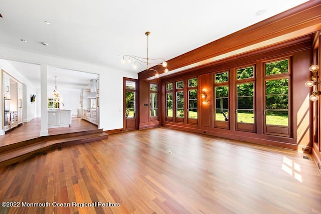 unfurnished living room featuring baseboards, a chandelier, and a healthy amount of sunlight
